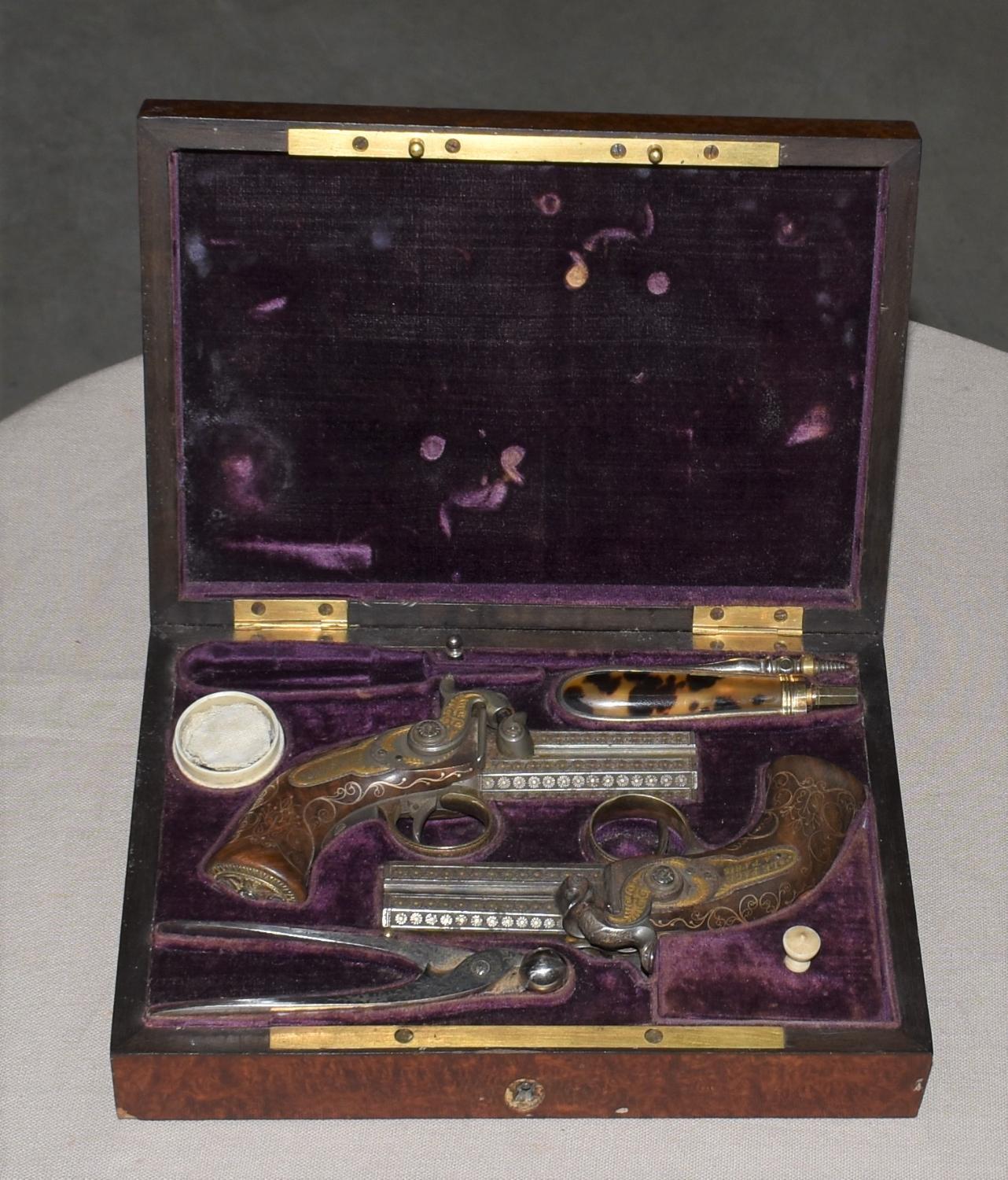 Coffret contenant un ensemble de deux pistolets, une poire à poudre et un moule à balles