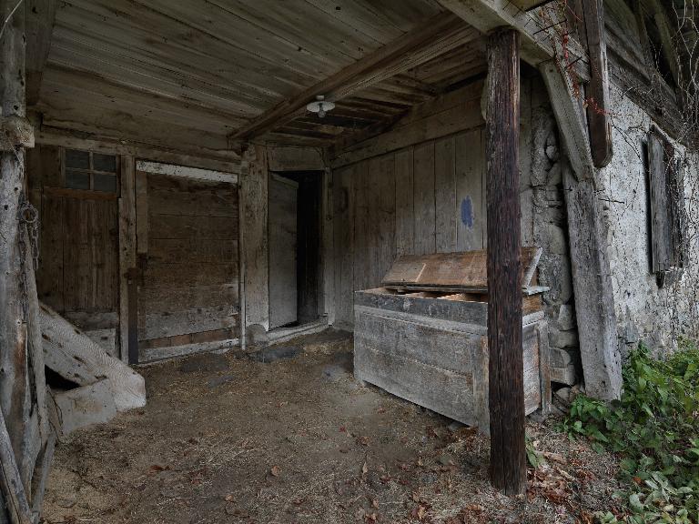 Partie est : porte d'entrée de l'habitation et porte du cellier ou étable ; coffre à grain devant le mur en retour.