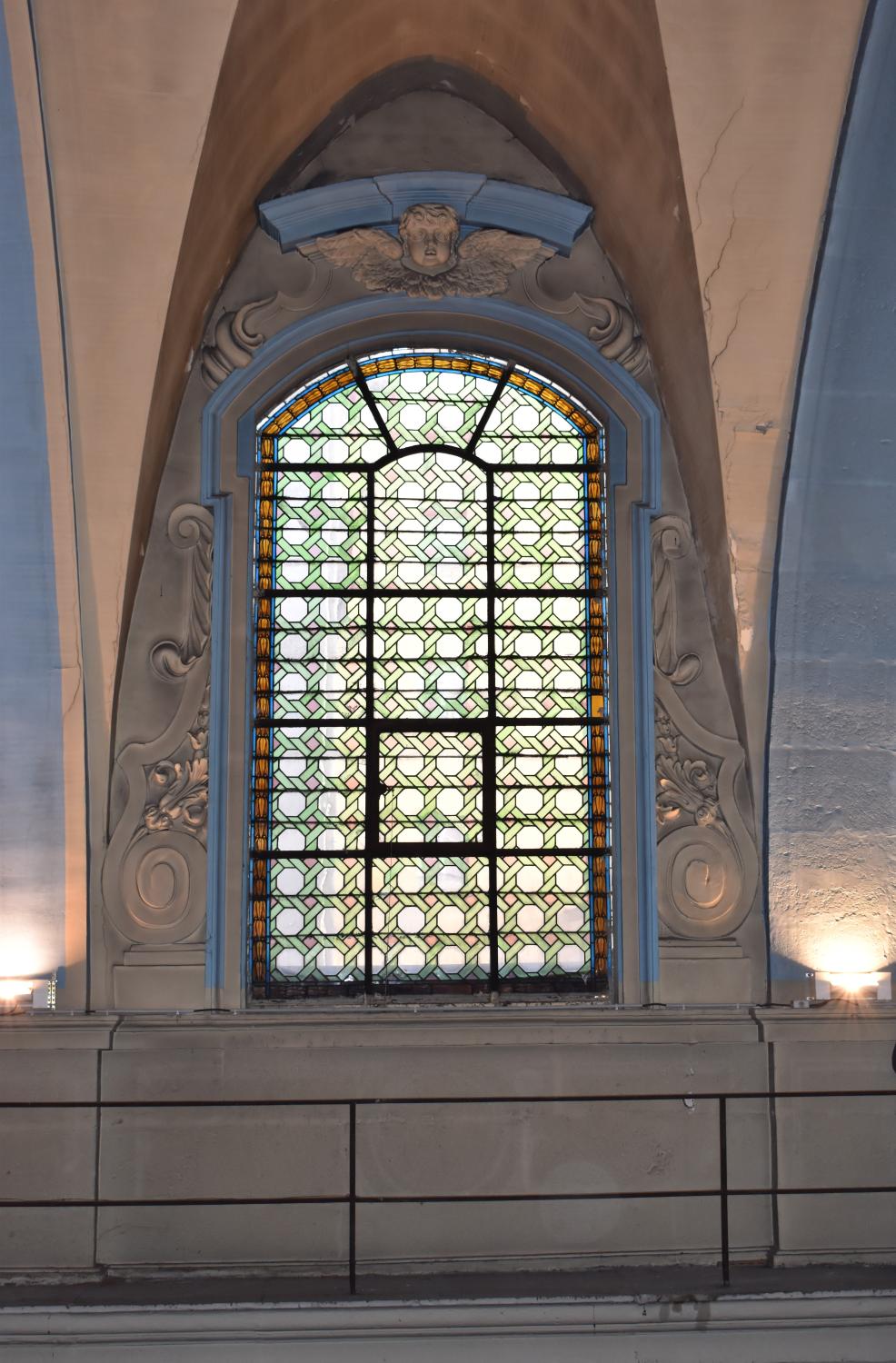 Vue d'ensemble d'une fenêtre haute à arc segmentaire, verrière à grisaille et son décor sculpté
